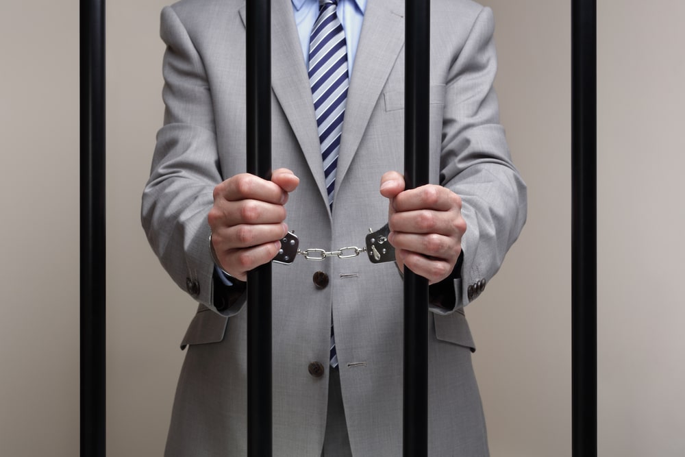 Businessman behind bars in prison concept for white collar crime