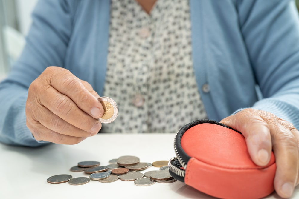 Asian senior or elderly old lady woman holding counting coin money in purse. Poverty, saving problem in retirement.